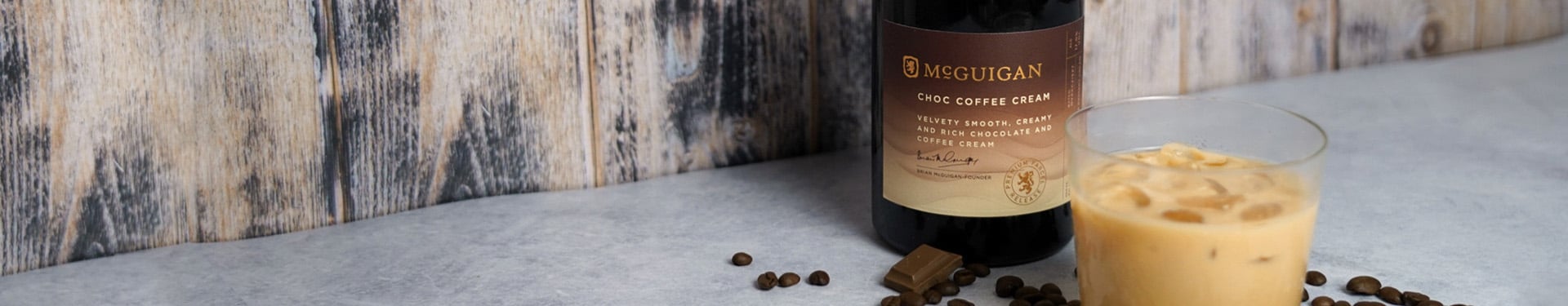 Bottle of and glass of McGuigan Choco Coffee Cream against a wooden wall