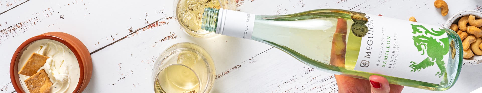 Bottle of wine pouring into glass with food next to it