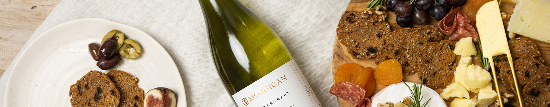 McGuigan Mastercraft Viognier lying flat in an indoor table setting with a cheeseboard